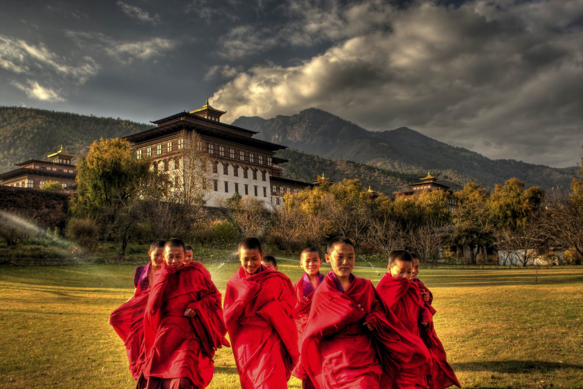 Young Bhutanese monks in red robes in front of a dzong