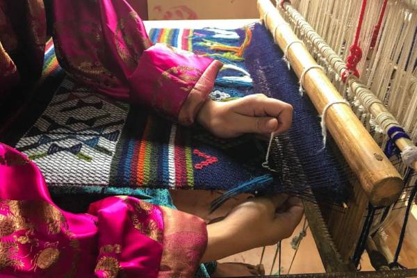 Bhutanese woman weaving a colourful textile on a traditional loom